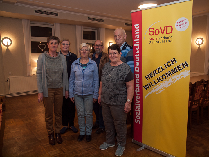 Vorstandsfoto des SoVD Horstedt vor dem Plakat des SoVD